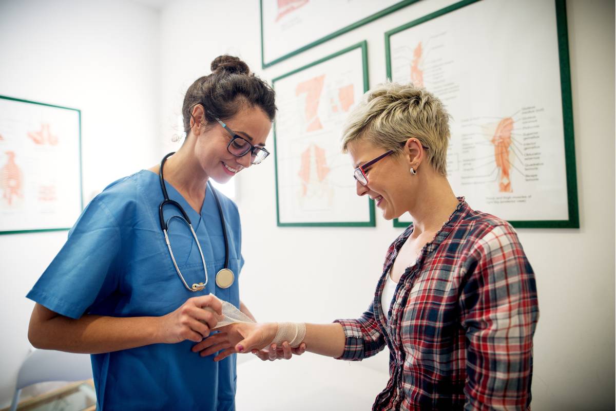 A nurse with CWS certification bandages a patient's hand.