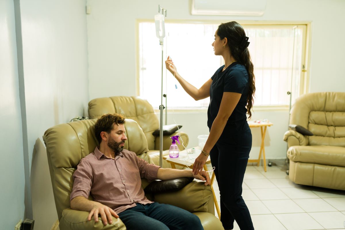 A detox nurse helps a patient with an IV.