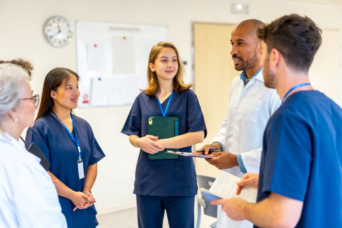 Nurses and doctors, standing in a meeting room as they conduct an ethics round.