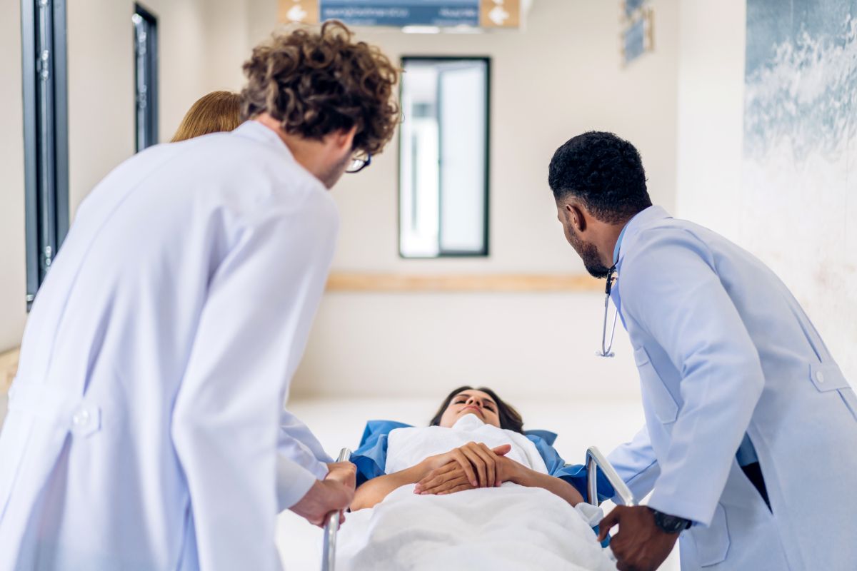 Physicians transport a patient lying on a stretcher.