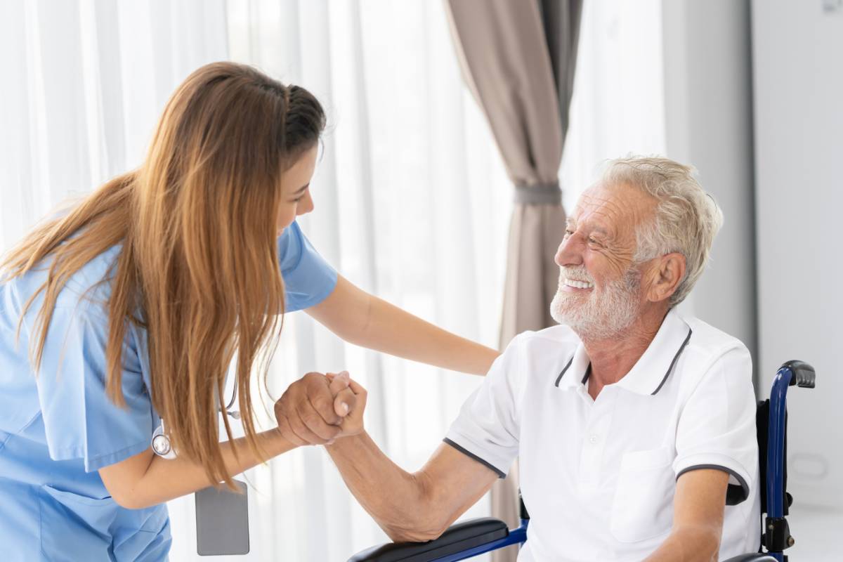 A geriatric nursing assistant helps a patient in a wheelchair.