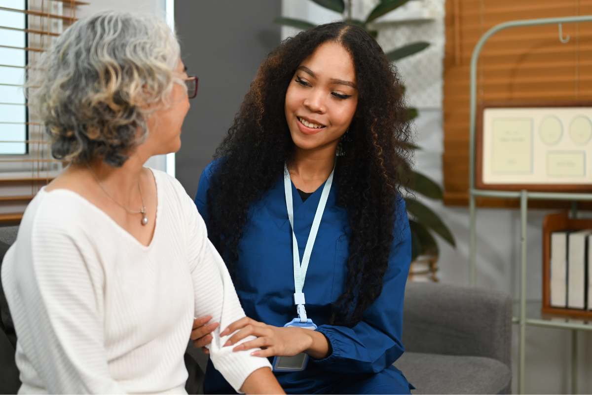 Female nurse in blue scrubs using Gordon's functional health patterns to assess an elder female patient.