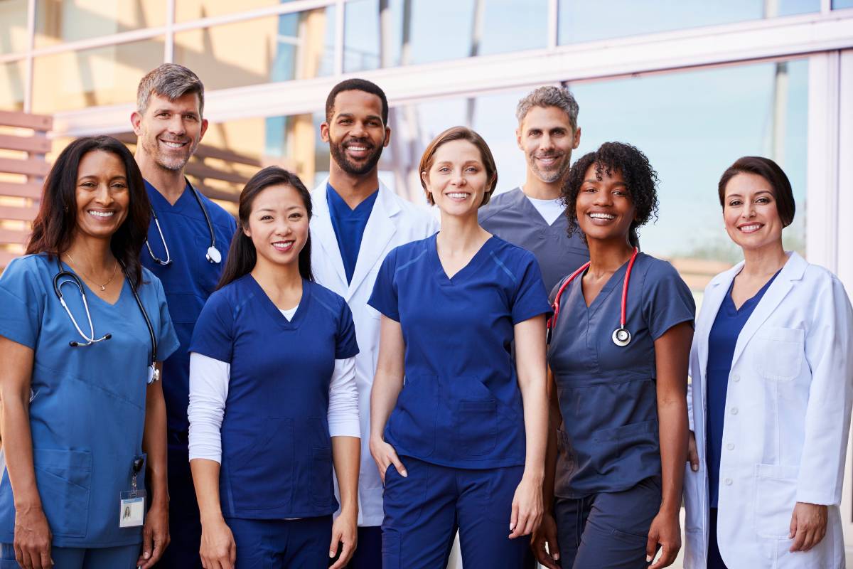 A group of nurses in the happiest nursing jobs smile as a group.