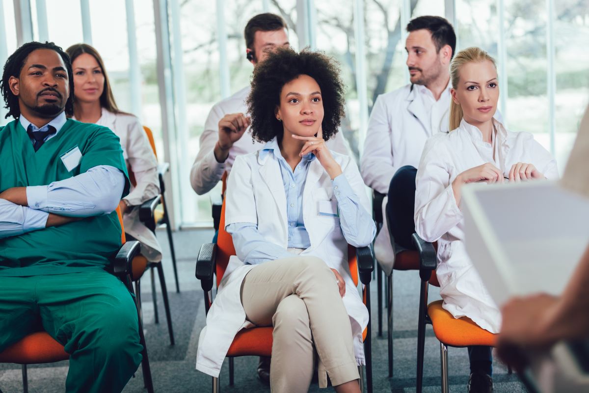 A group of nurses and physicians listen to a symposium during a healthcare conference.