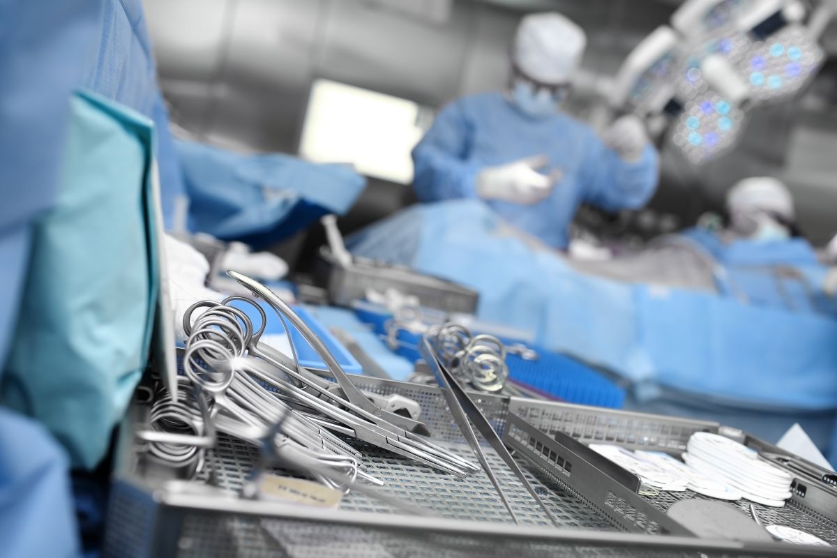 A close-up picture of surgical tools, with doctors and nurses in the background.