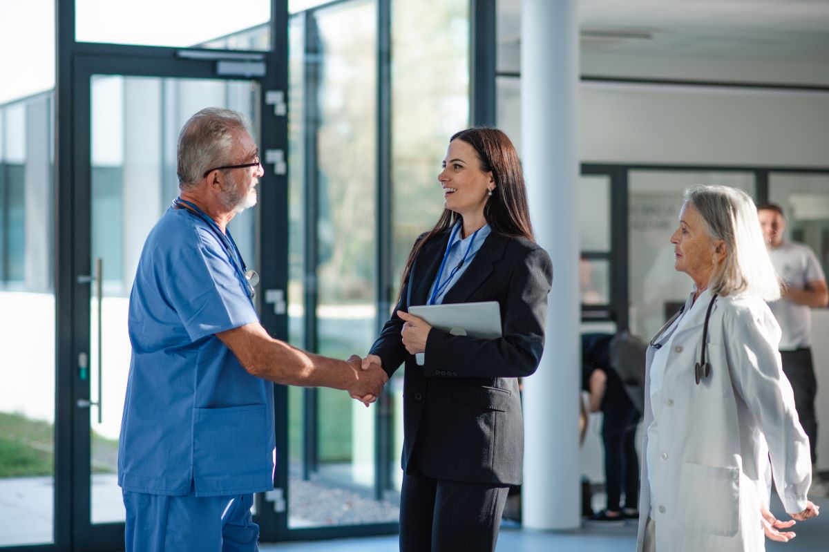 A businesswoman meets with a senior member of the hospital staff to discuss a HIPAA business agreement.