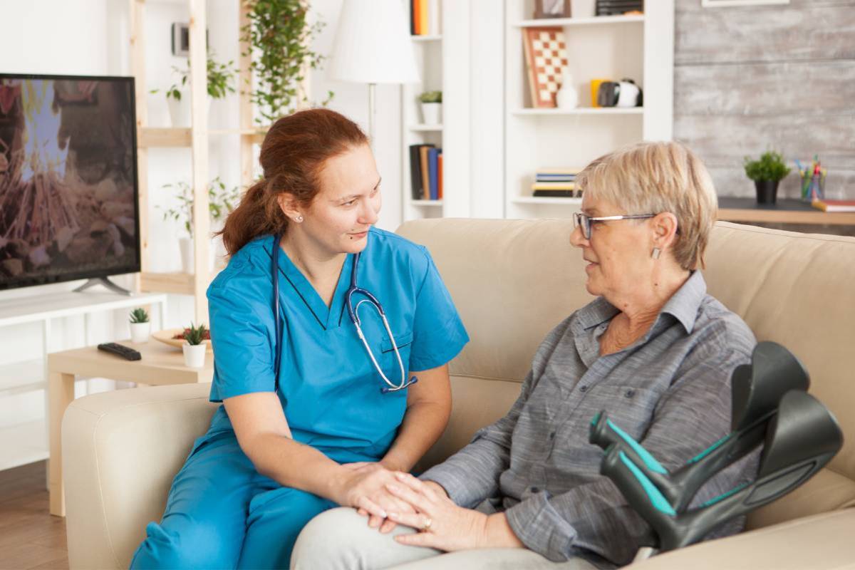 A hospice nurse practitioner speaks with a patient in their home.
