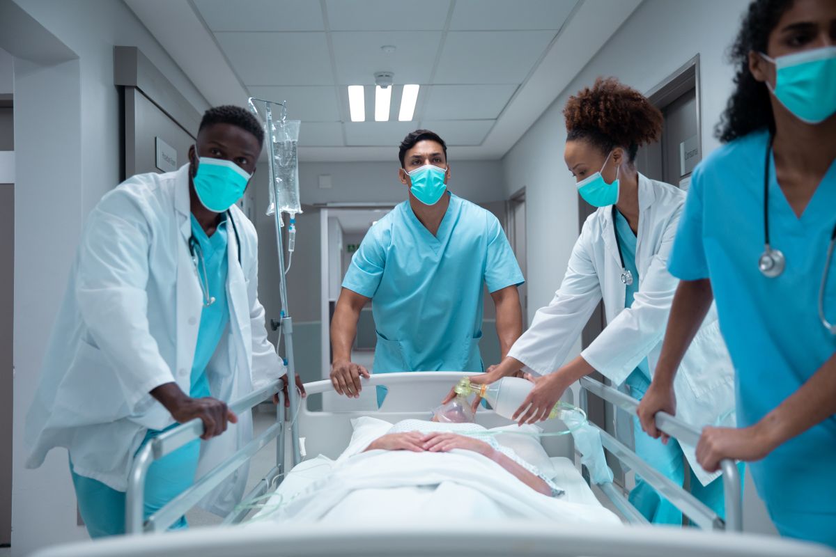 Nurses and doctors assist a patient as he's prepped for surgery and taken down the hospital hallway.