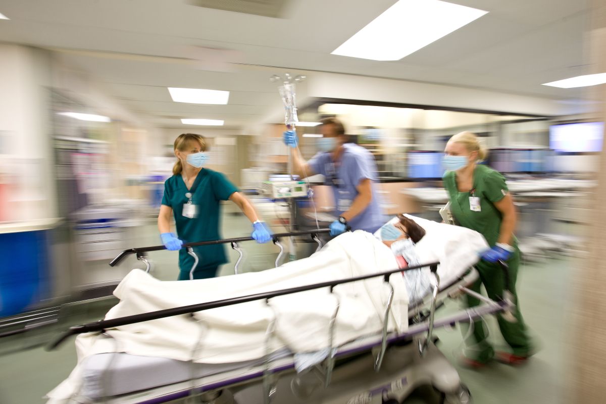 A team of doctors and nurses rushes a patient down the hall, after issuing a hospital emergency code.