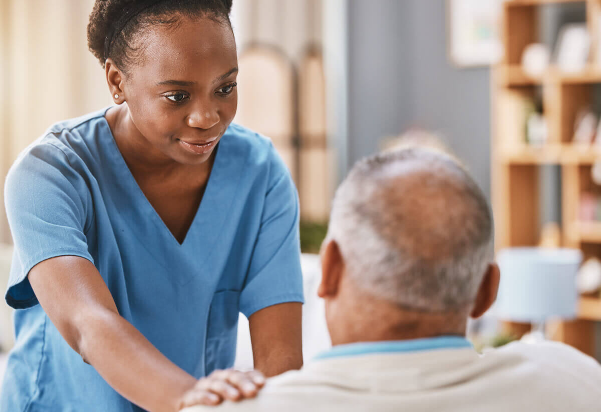 African-American nurse with her hand on the shoulder of a senior patient.