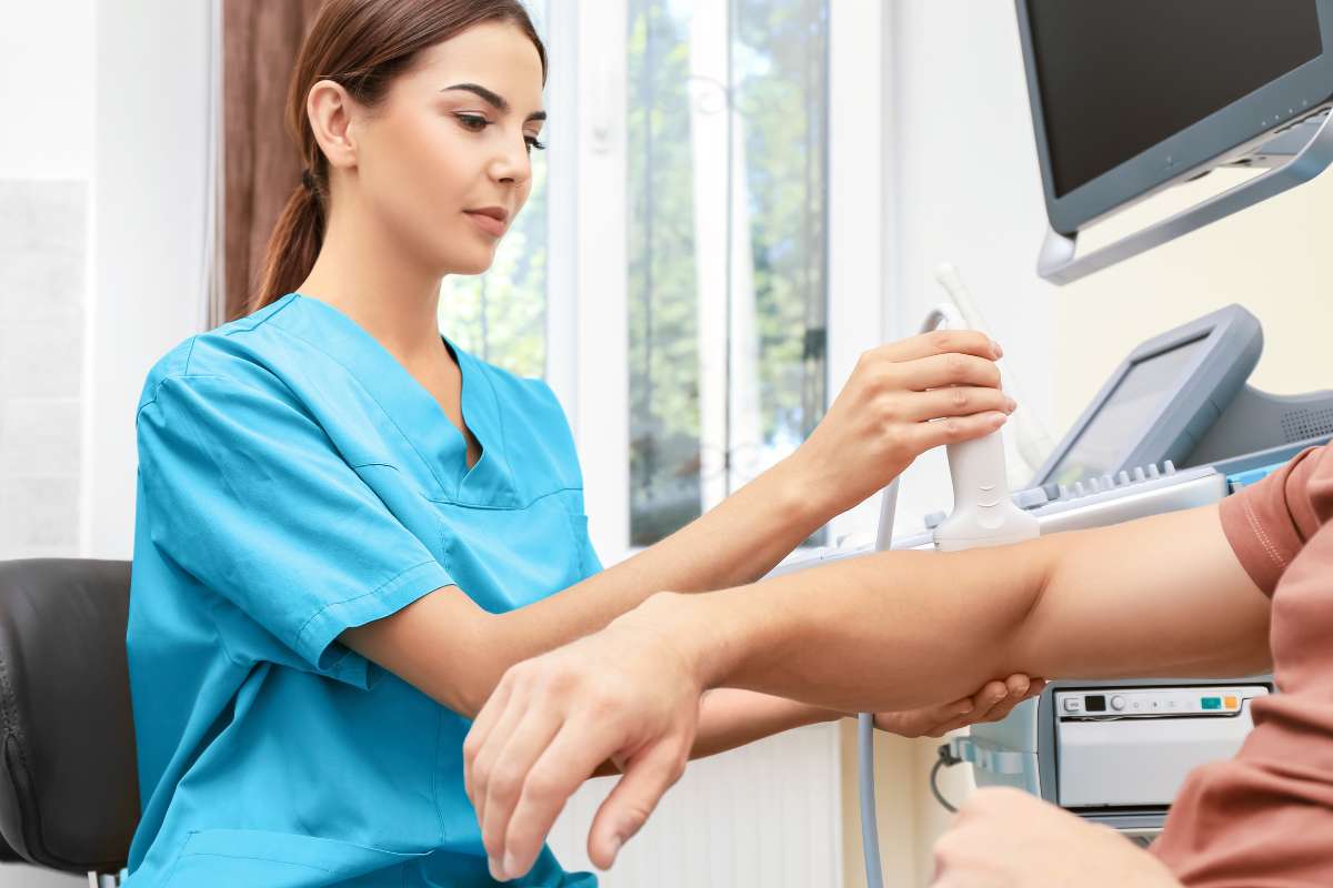 Female sonographer taking an ultrasound of a patient's arm.