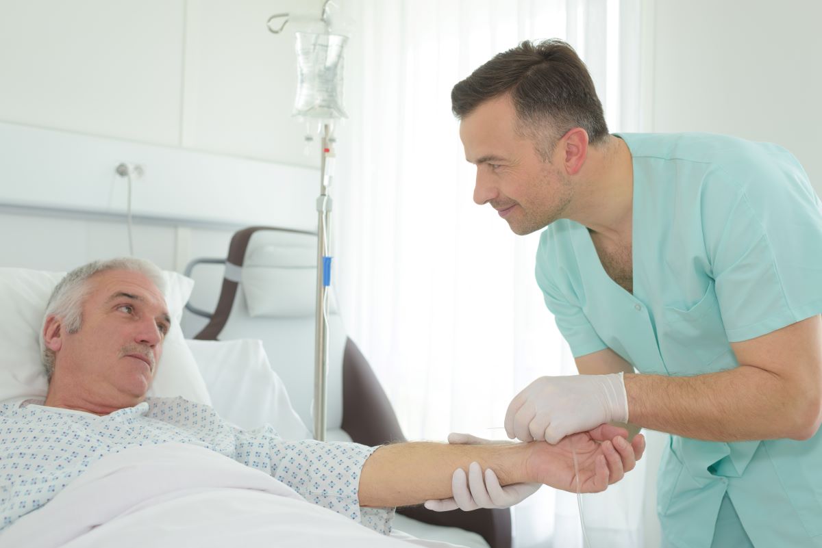 An infusion nurse helps his patient with an IV.