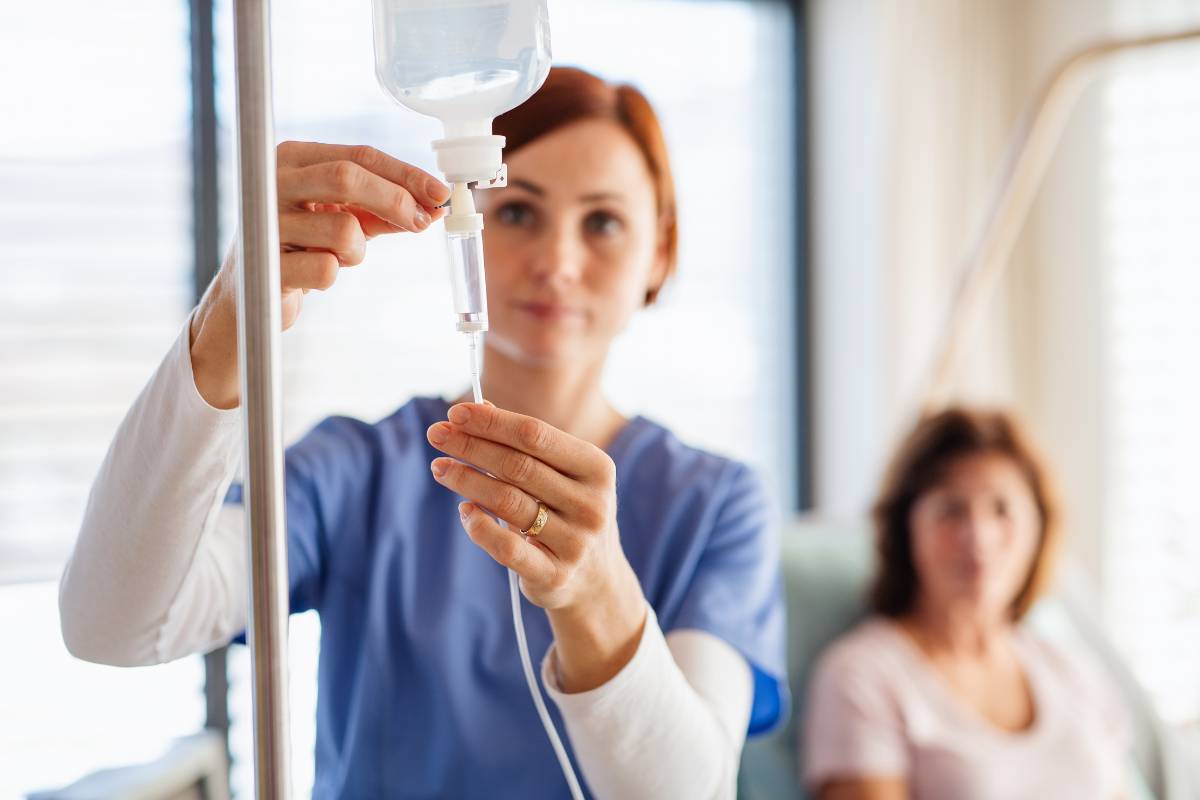 An infusion nurse hangs an IV bag.