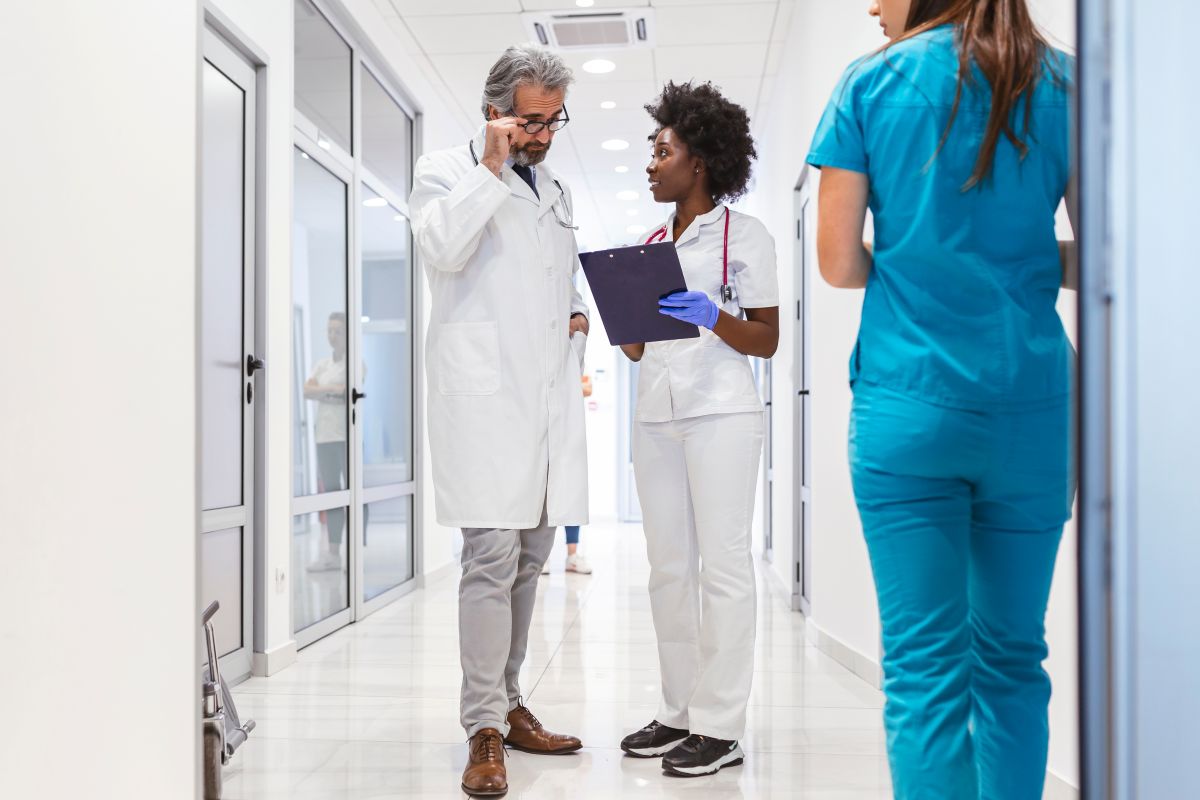 A DNP meets with a physician in the hallway of a hospital.