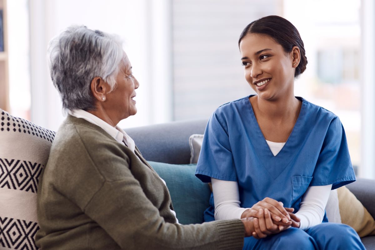 A nurse sits with a nursing home resident, providing comfort and companionship.
