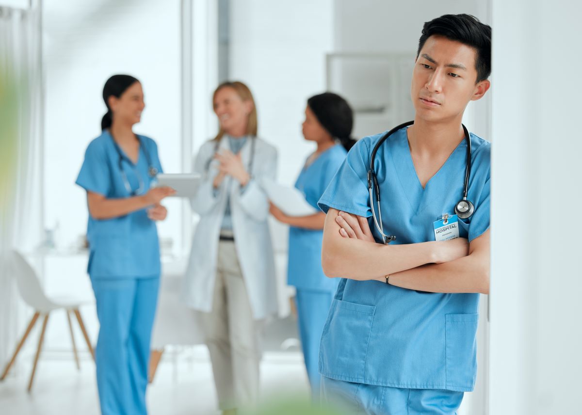 A nurse stands alone, while his colleagues carry on together.