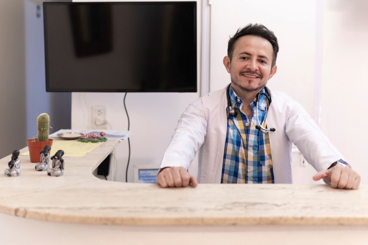 A healthcare worker sits behind the counter of his clinic.