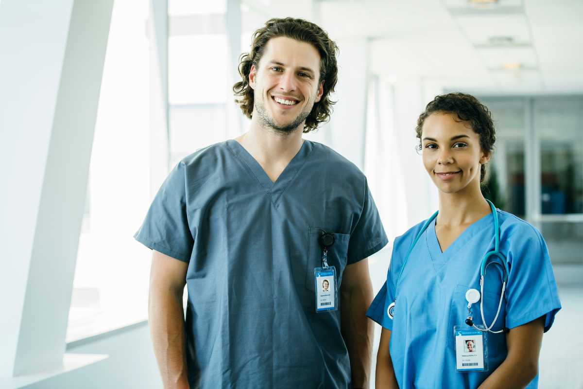 Male and female LPNs in a hospital hallway.