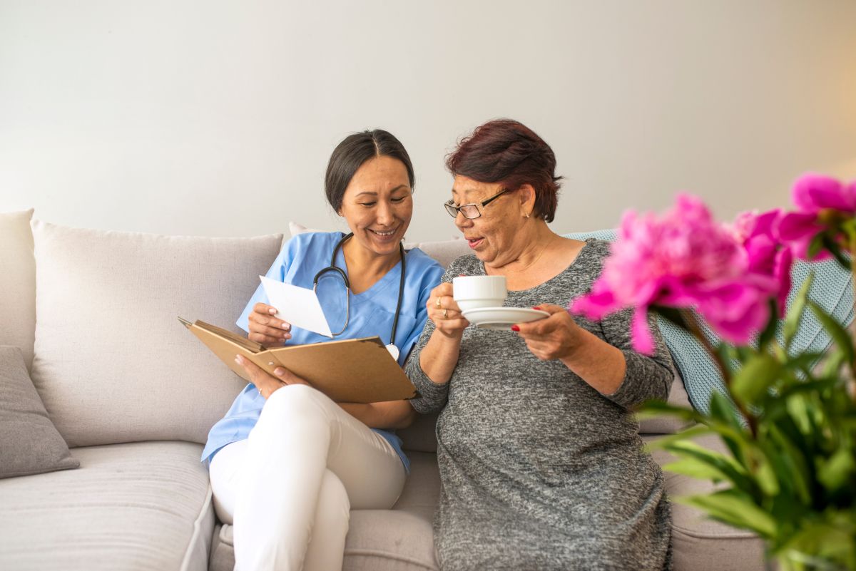 A memory care nurse sits with one of her patients and has a conversation.