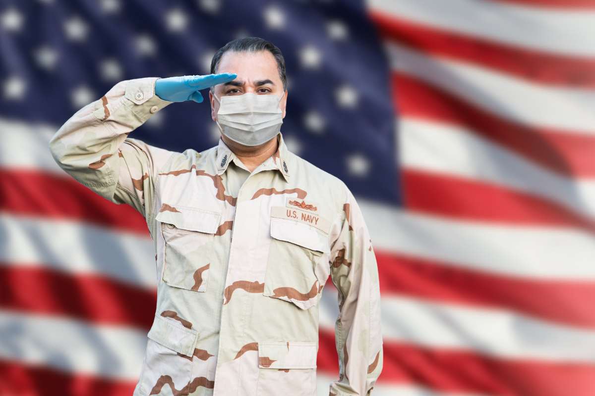 Navy nurse saluting in front of the American flag.