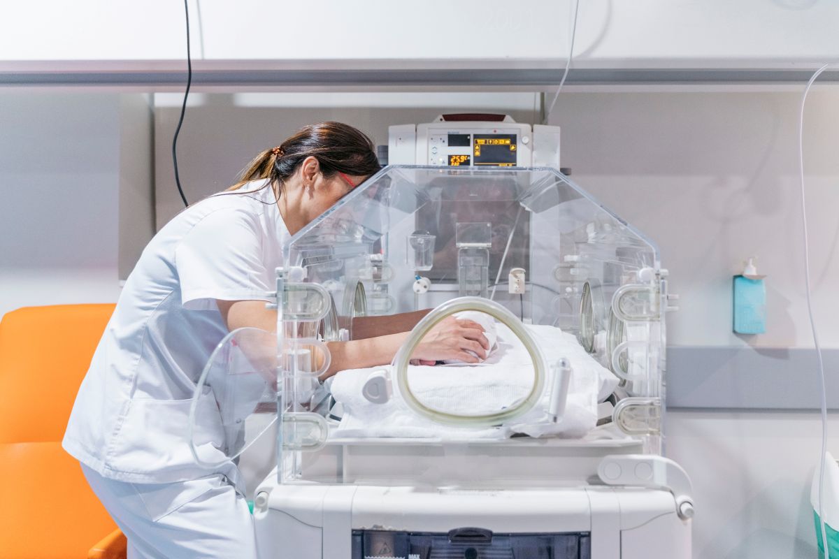 A neonatal nurse practitioner checks in on a premature infant.
