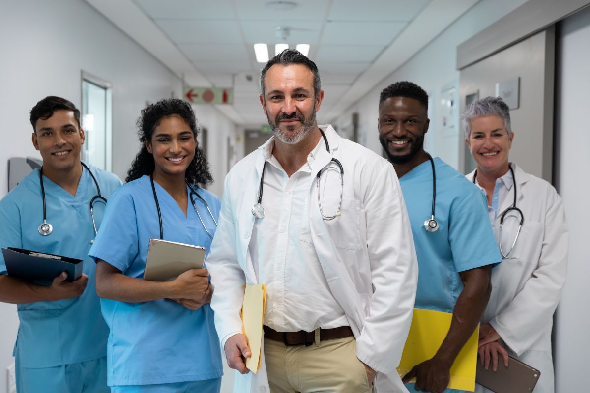 Nurses and doctors pose for the camera in a hospital's hallway.