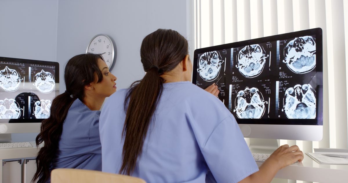 A nuclear med tech and a nurse look at brain scan images.