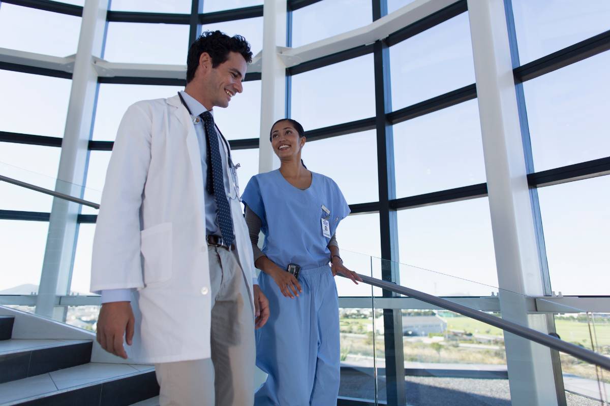 A nurse advocate speaks with a physician in a hospital stairway.