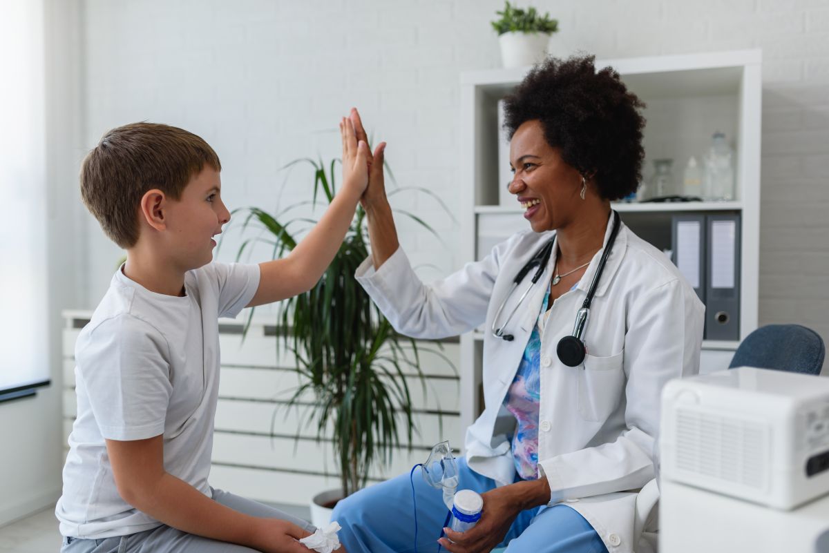 A nurse practitioner high-fives one of her child patients.
