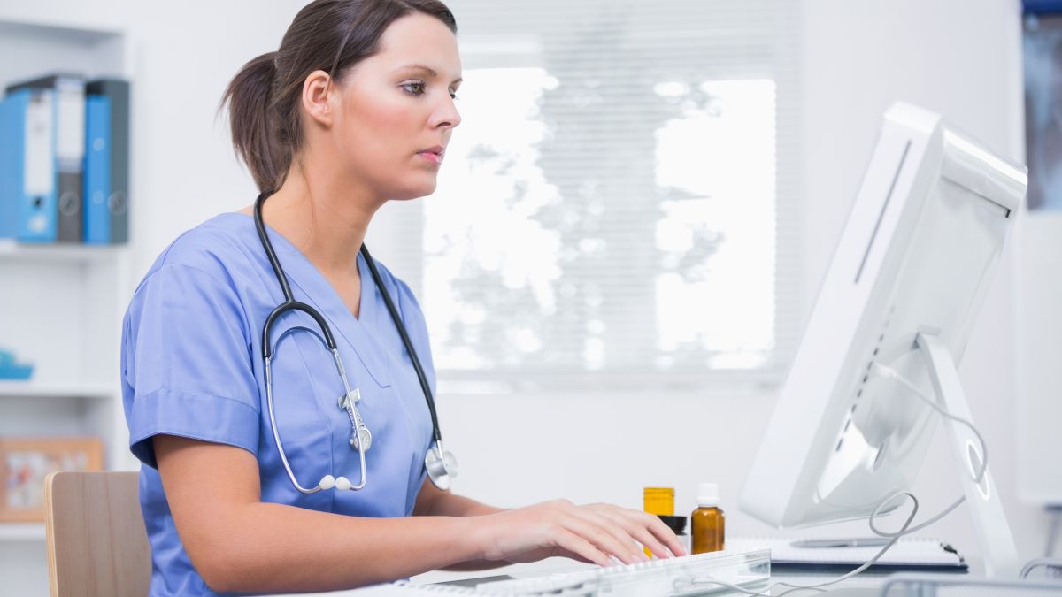 A nurse sits at the computer and types a nurse recommendation letter for a former colleague.