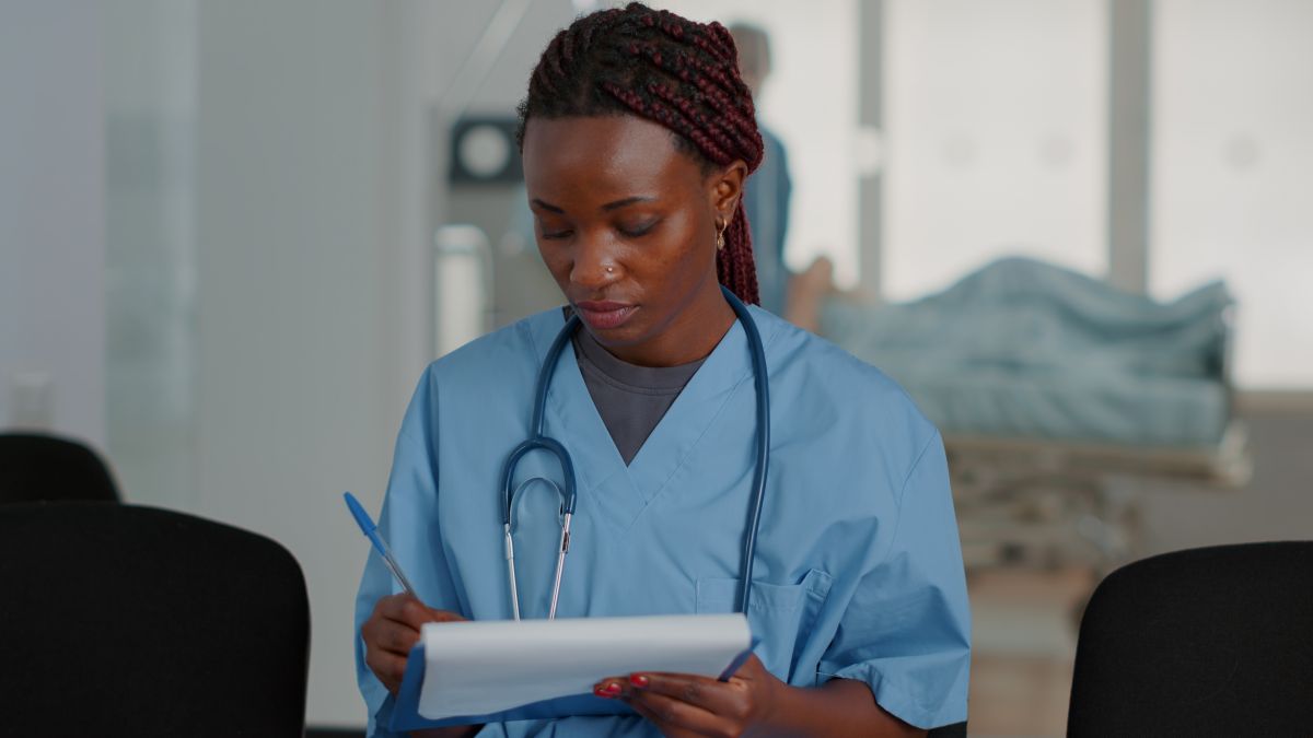 An OB-GYN nurse takes notes as she meets with a patient.
