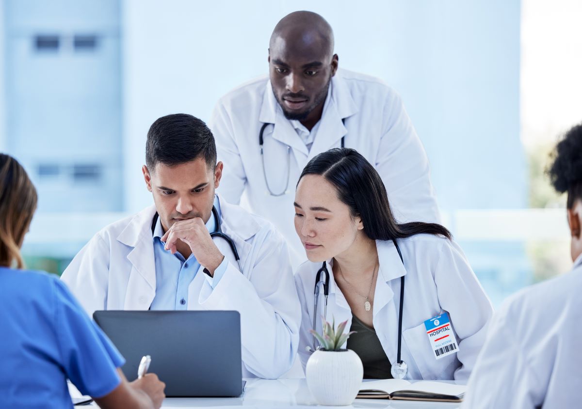 Three healthcare workers reading a healthcare ombudsman's report on a laptop screen.