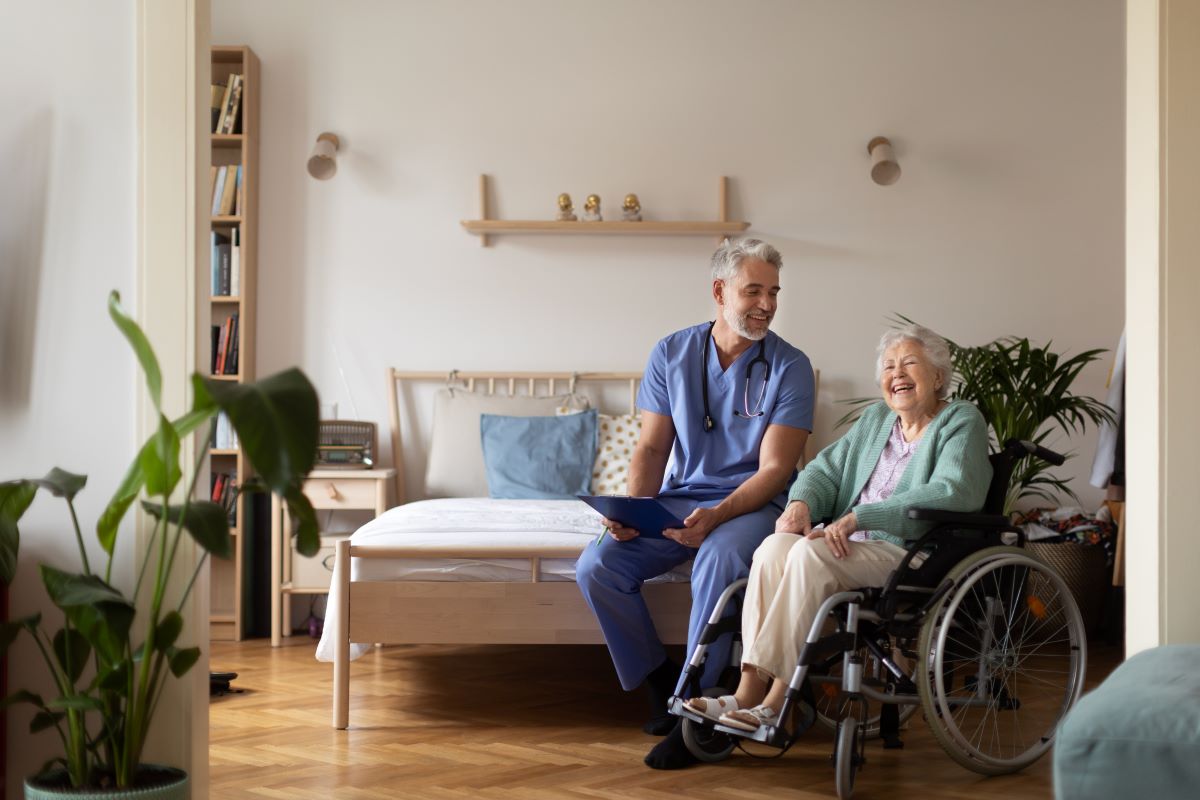 A nurse meets with one of his elderly resident patients in her room.