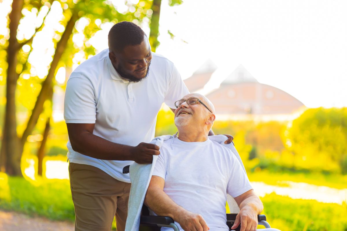 Patient care associate helping man in wheelchair outside