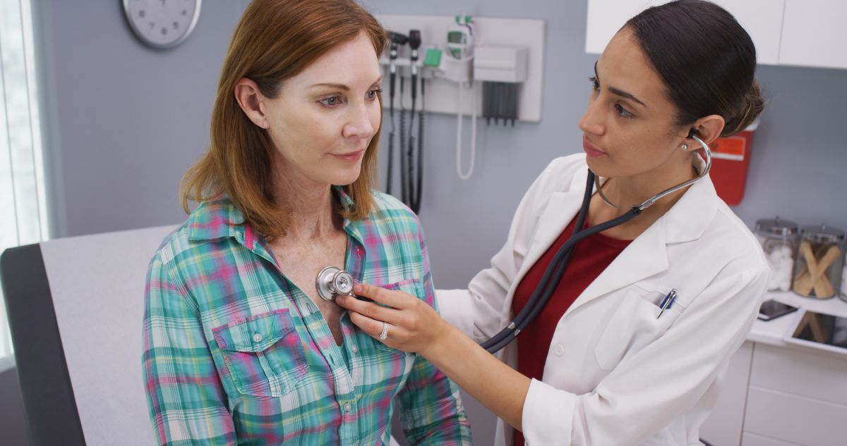 A physician checks her patient's heart rate.