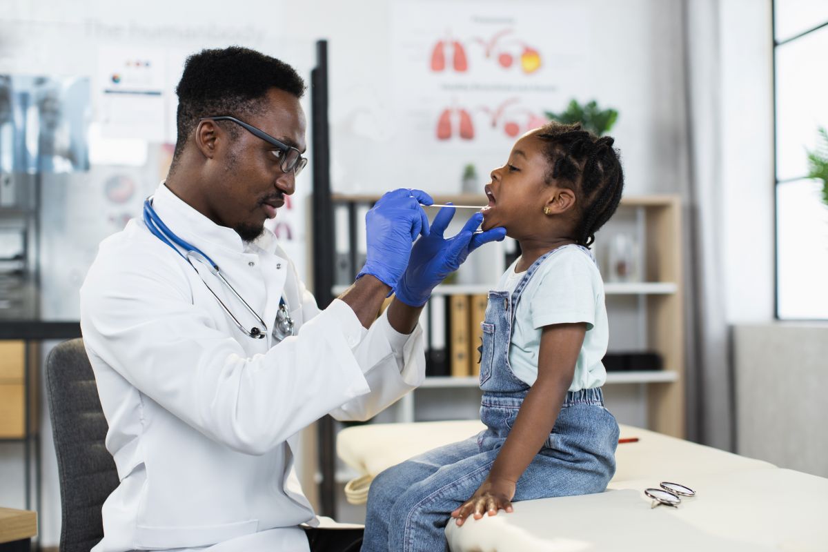 A pediatric physician checks a patient's tonsils.