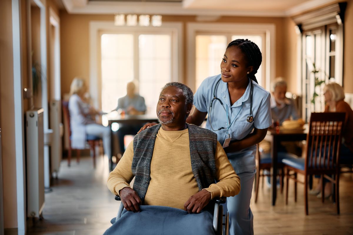 A nurse at a long-term care facility helps a resident move around.