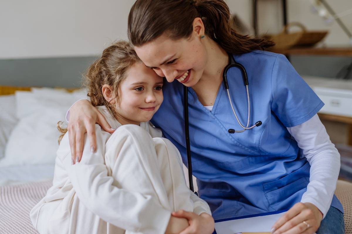 A pediatric home health nurse comforts a patient.
