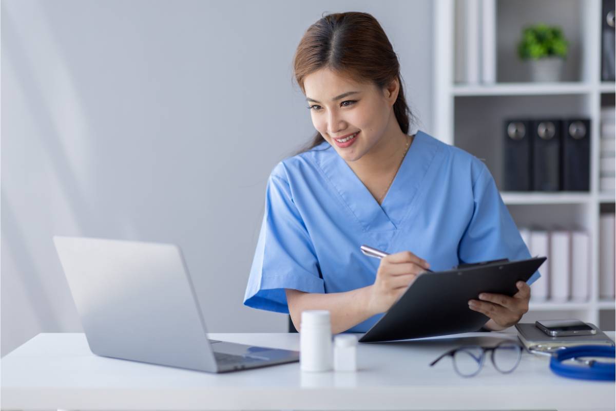 Nurse in blue scrubs writes their pediatric nurse cover letter.