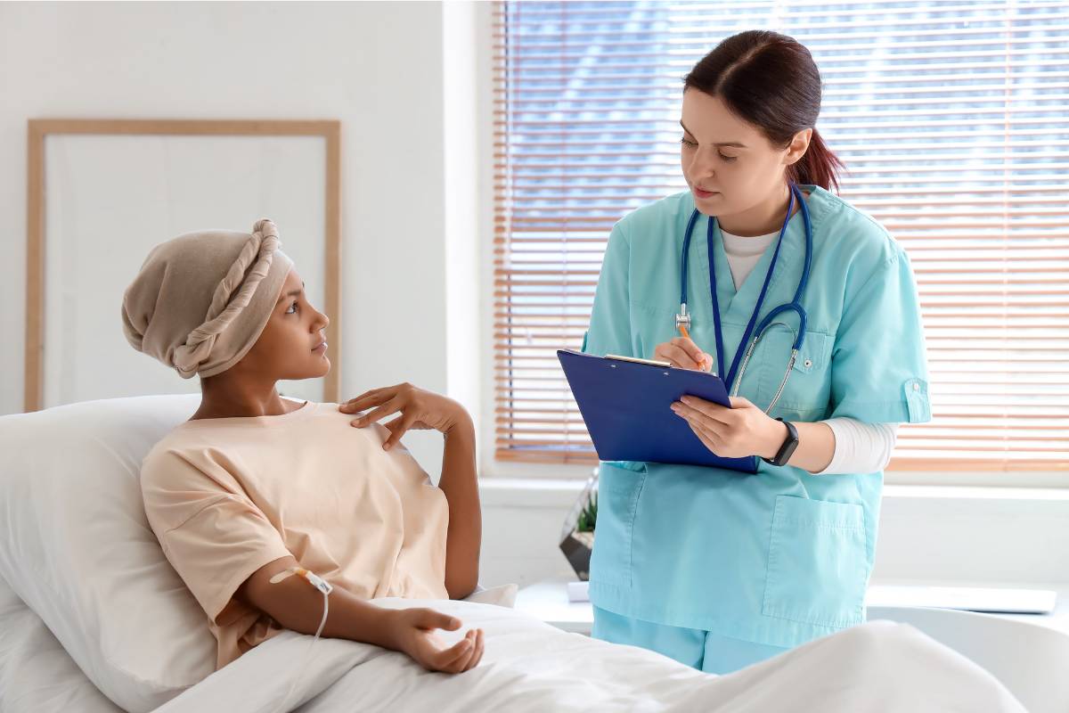 A pediatric oncology nurse speaks with an adolescent patient.