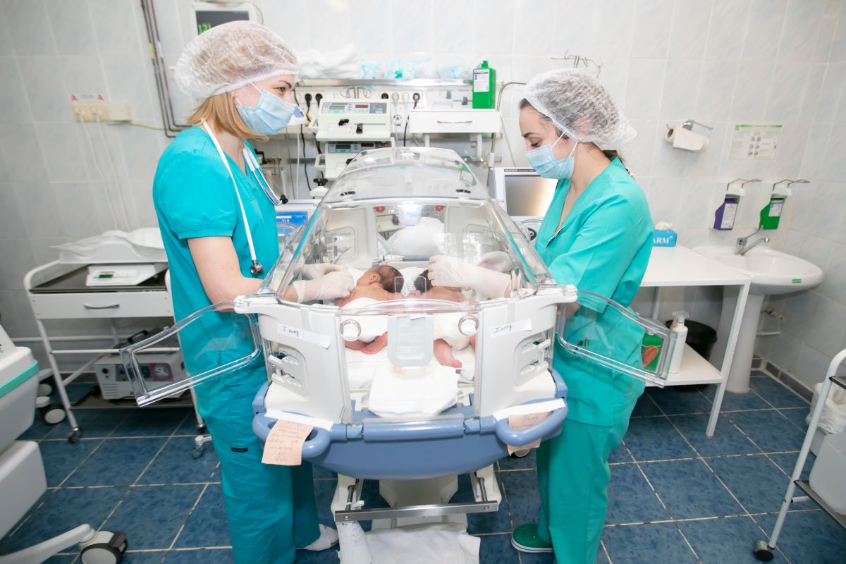 Two PICU nurses attend to an infant.