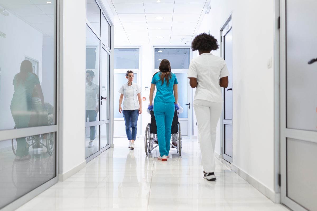 The view of a hospital hallway, with patients and healthcare workers.