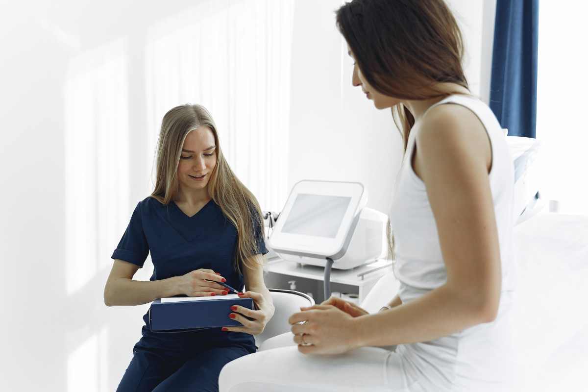 Psychiatric nurse reviewing form with a patient seated on a hospital bed.