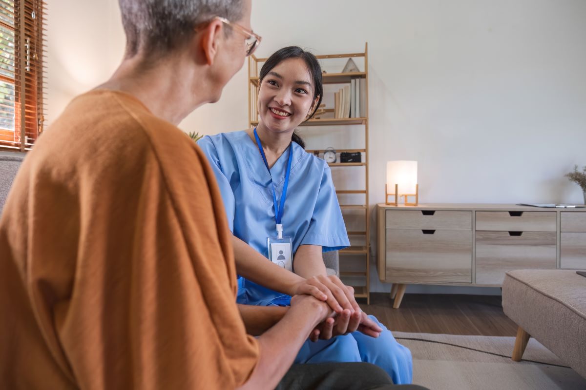 A psychiatric nurse holds the hand of one of her patients as she listens.