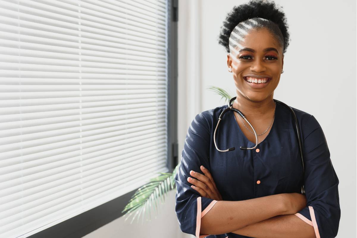 A nurse with RAC-CT certification poses for a photo by a window.