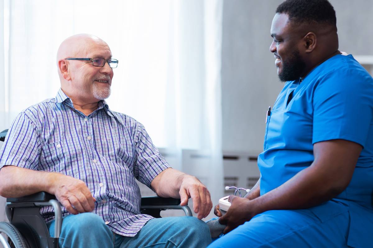 A rehab nurse communicates with a patient who is sitting in a wheel chair.