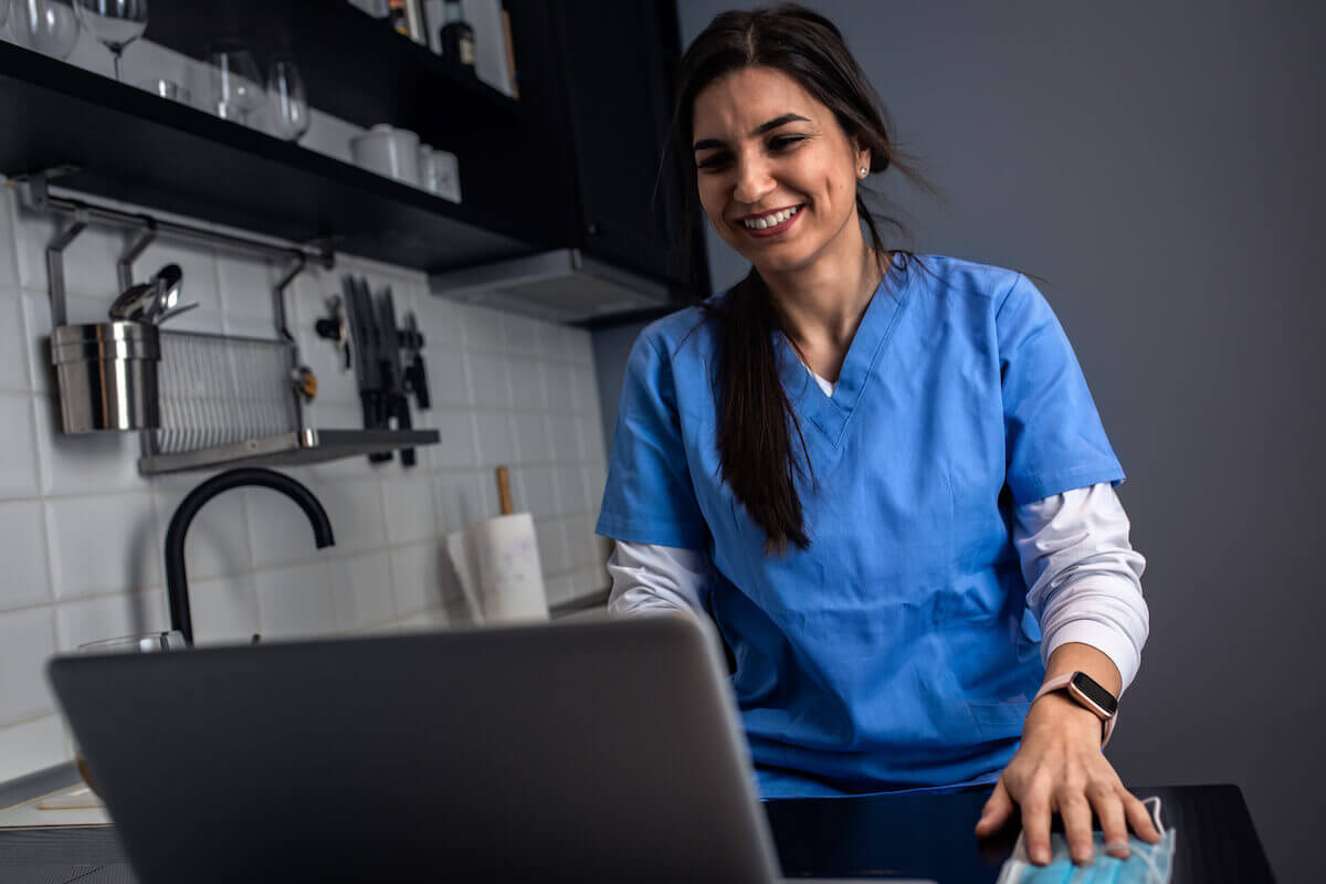 Nurse with long dark hair working on laptop to renew a nursing license in Illinois.