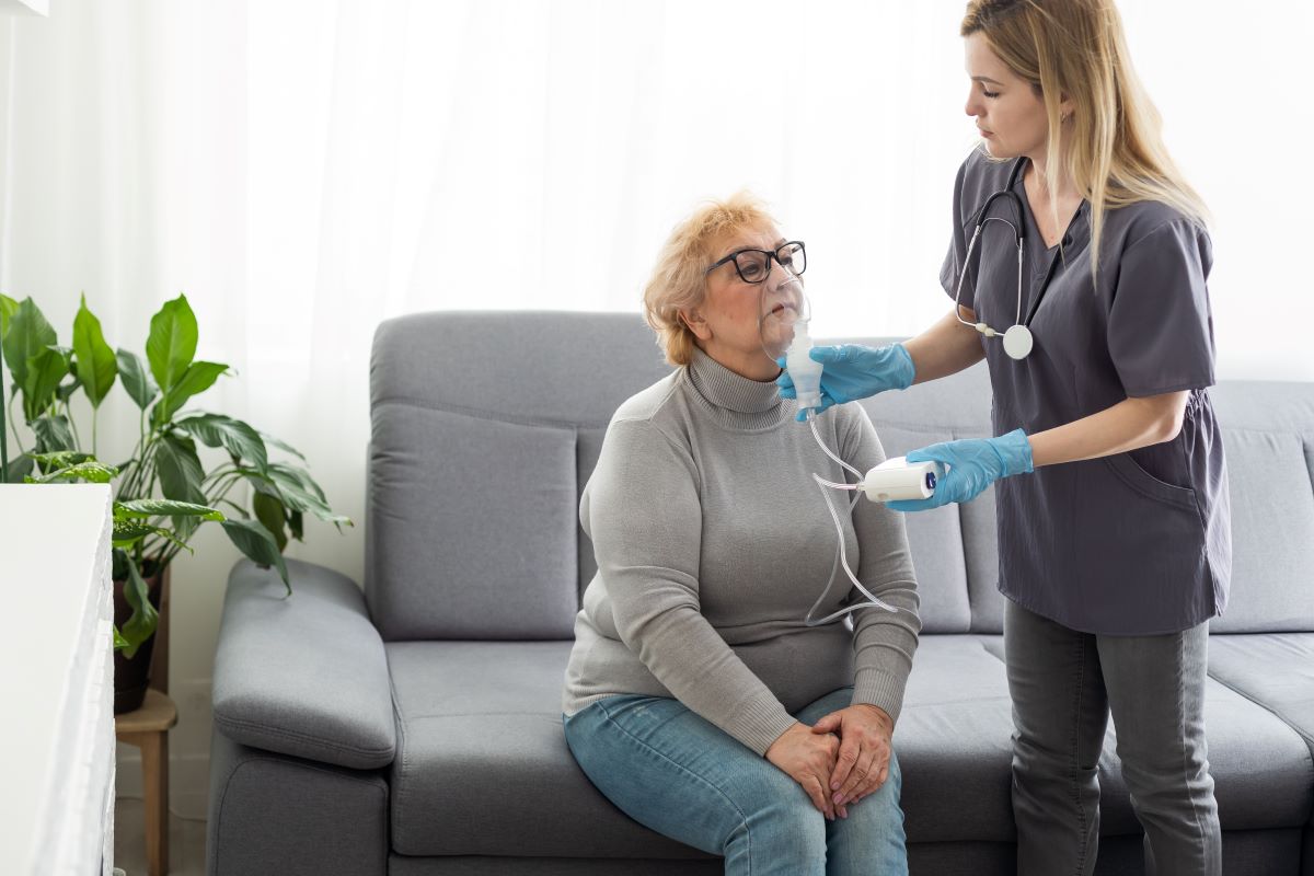 A respiratory therapist assists one of her patients with a CPAP mask.