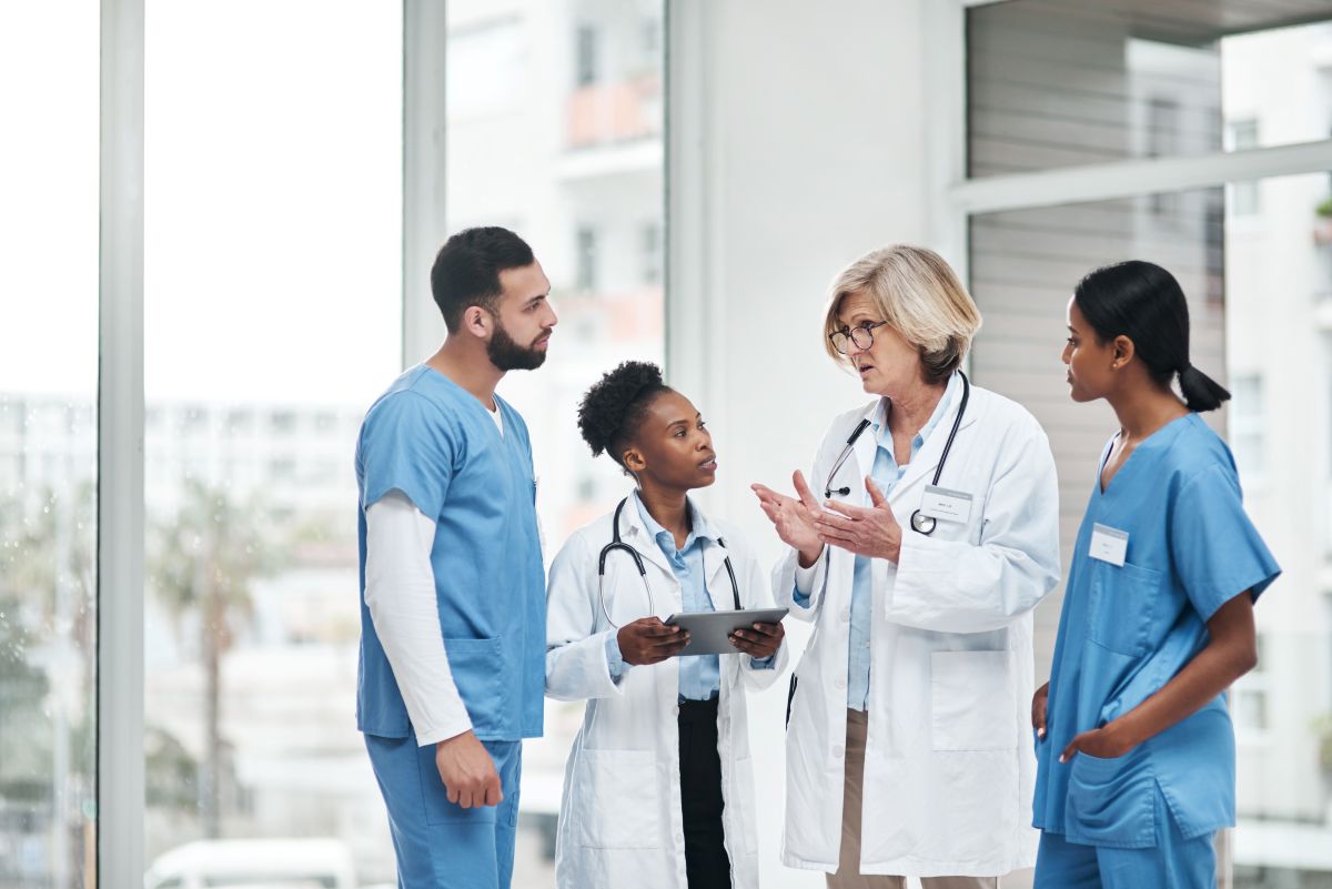 A physician discusses risk management measures with another physician and two nurses.