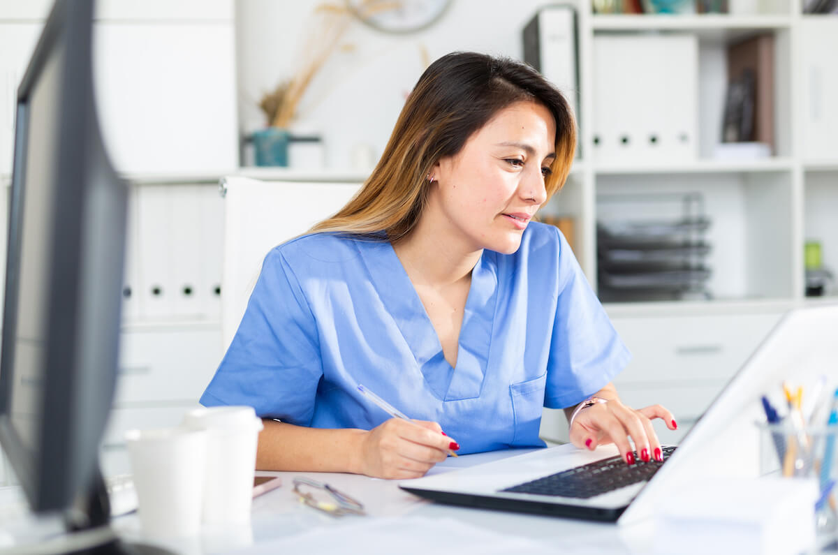 Latina nurse working on her cover letter on a laptop.